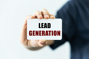 Lead generation  text on blank business card being held by a woman's hand with blurred background. Business concept about lead generation.