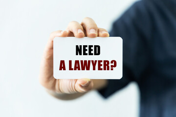 Need a lawyer question text on blank business card being held by a woman's hand with blurred background. Business concept about lawyer requirement.