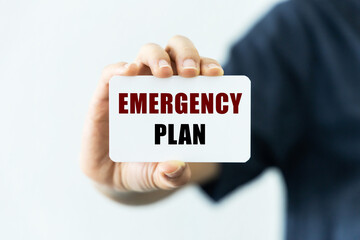 Emergency plan text on blank business card being held by a woman's hand with blurred background. Business concept about emergency plan.