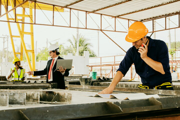 Caucasian businessman and male and female workers working on construction site under indoor roof precast concrete wall factory : Architect worker planning work according to blueprint.