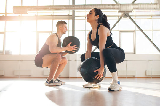 athletic couple in sportswear at crossfit training with ball in the room, woman and man together at fitness training