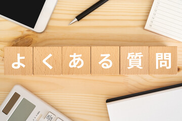 よくある質問と書かれたブロック、電卓、スマホ、カレンダー
