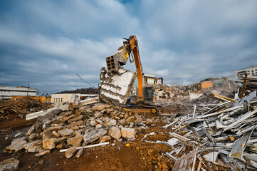 Fototapeta premium Excavator with hydraulic press breaks concrete leftovers
