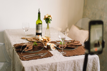A young woman is filming kitchen goods for her online store on her phone camera. Running a video blog. A vlogger broadcasts online using a phone. Social networks,stay at home and quarantine.