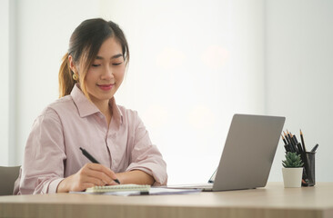 Thoughtful asian businesswoman checking financial reports at her office desk..