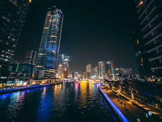 Fototapeta na wymiar Dubai Marina, harbour, cruise boat and canal promenade view at night, in Dubai, United Arab Emirates