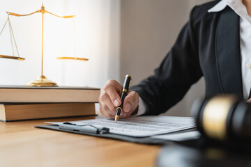 Asian female legal advisor or a lawyer using a pen to check business information and various details Business venture capital acknowledgment signing on paperwork at a desk in her office.
