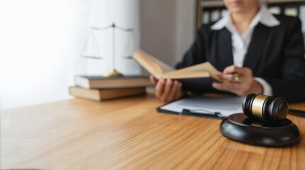 lawyer, legal advisor ,Businesswoman using a pen and reading a book of law codes Justice in real estate on works with a hammer Scales and signing documents in the office.
