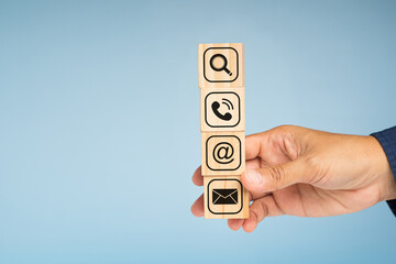 Hand businesspeople holding wooden cubes with symbols of a magnifying glass, mobile, address, and...