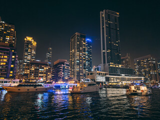Obraz premium Dubai Marina, harbour, cruise boat and canal promenade view at night, in Dubai, United Arab Emirates