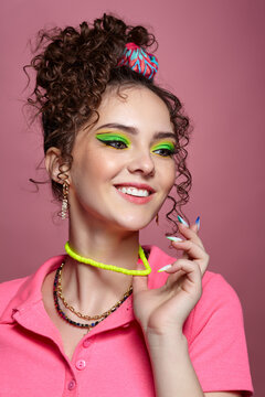 Young woman on pink background with green eyes makeup and curly hair.