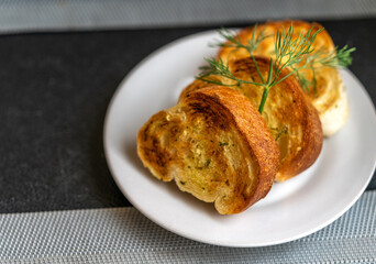 Tasty sliced bread with garlic on a white plate on a table in a restaurant, crispy tasty bread with garlic.
