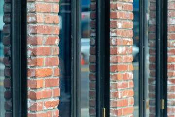 Row of glass windows with red exterior brick facade in late afternoon shade in city or downtown area of neighborhood