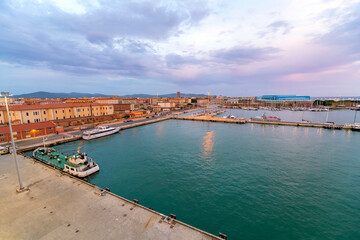 Fototapeta na wymiar View of the waterfront promenade and cityscape at the cruise port harbor of Livorno, Italy, at dusk.