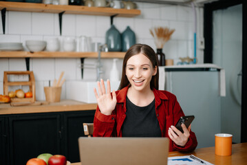 Young beautiful woman typing on tablet and laptop while sitting at the working wooden table modern office.