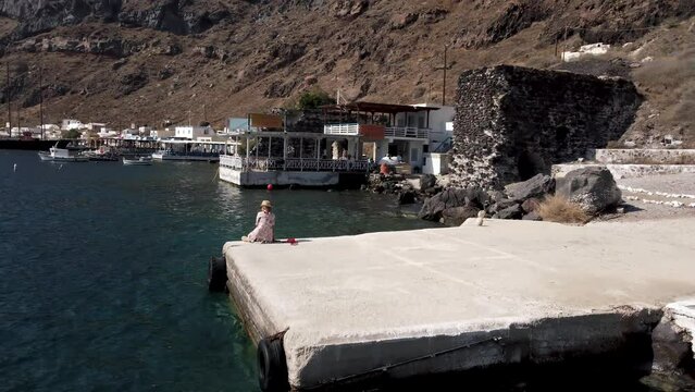 Drone video of a woman at Thirasia port Santorini in summer