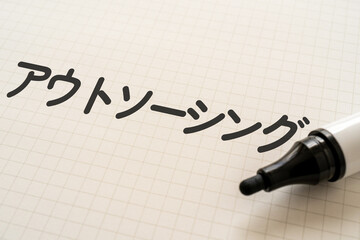 アウトソーシングと書かれたノートとマーカー
