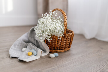 A basket of twigs with white flowers, a towel, blue, yellow, white eggs. Spring Background for Easter