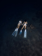 Girls freedivers dive together in deep ocean. Freediving with couple in underwater