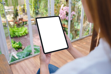 Mockup image of a woman holding digital tablet with blank white desktop screen in cafe