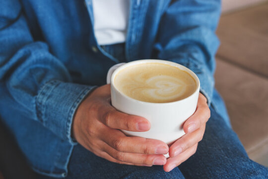 Closeup image of a woman holding a cup of hot latte coffee