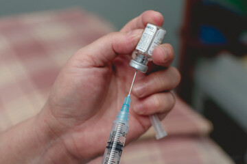 A doctor fills a syringe with rabies vaccine from a vial while at the emergency room. Closeup on...