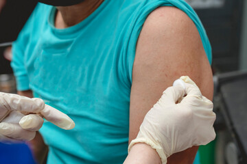 Fototapeta premium A doctor wipes the shoulder of a dog bite victim with alcohol before giving a rabies shot at the emergency room.