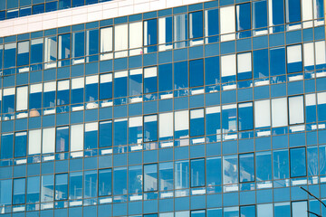 Modern office building facade. Tall business center with a glass facade. Construction of a glass facade structure. The glare of the sun on the glass wall of a skyscraper