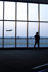 Fototapeta na wymiar Silhouette of a man standing in front of the window at the airport