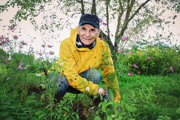 Portrait of positive smiling farmer working in flowerbed. Gardening and horticulture concept.