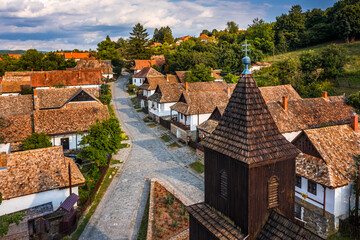 Holloko, Hungary - Aerial view of the tower of the traditional catholic church of Holloko at the village centre, an UNESCO site in Hungary on a sunny summer day with cluds and blue sky