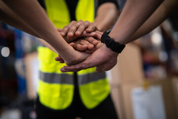 Close up view of warehouse workers putting their hands together. Stack of hands. Unity and teamwork.