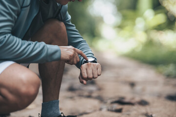 sport man checking at smartwatch during training and running in the park. Outdoor workout,  Healthy lifestyle concept.
