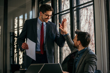 Image of a mid adult manager having a brief meeting with his young associate at the office. They are having lively conversation and they seem to agree about certain points of interest.
