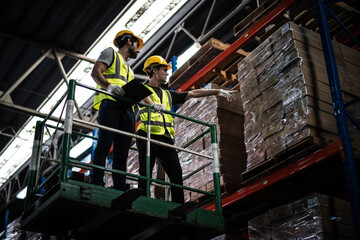 Caucasian warehouse workers with clipboard standing on scissor lift near shelves with clipboard Checks Stock and Inventory in the Retail Warehouse.