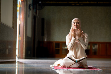 The image of an Asian Muslim woman in the Islamic religion in hijab in cream color. She was praying in a beautiful mosque out of respect for God.