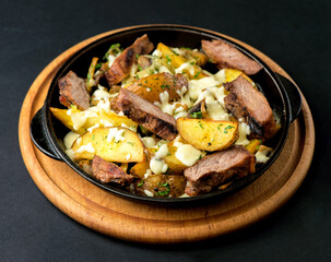 potatoes with meat and cheese baked in the oven on a dark background