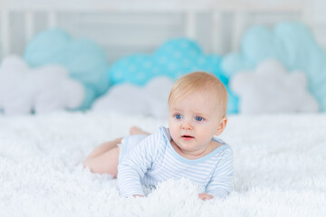 baby on the bed in blue pajamas goes to bed or wakes up in the morning, baby boy blonde six months