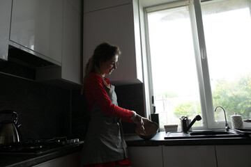 woman cook cooking in a bowl of food in the kitchen by the window