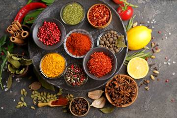 Set of spices and herbs. Indian food. Pepper, salt, paprika, basil, turmeric. On a black wooden board. View from above. Free copy space.