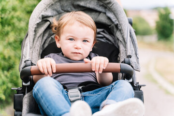 Portrait of a small kid sitting inside a baby carriage