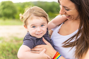 Kid in arms of a mother with a lgbt bracelet