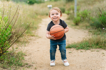 Cute little girl playing with a basketball ball