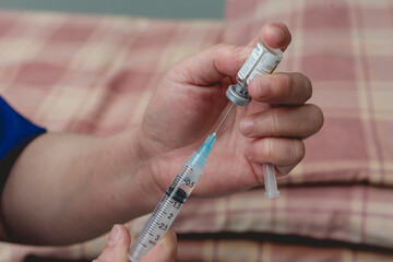 A doctor fills a syringe with rabies vaccine from a vial while at the emergency room. Closeup on hands and process.