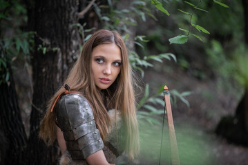 Beautiful girl an archer with the bow in the forest. Woman warrior concept.