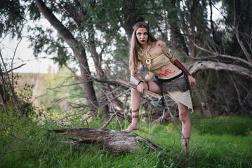 Beautiful girl warrior is hunting in the jungle with the axe concept.