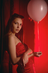 Beautiful girl in the red dress with the handgun in the red lights. Secret agent concept.