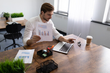 businessman studying the financial affairs of his company holding charts in his hands