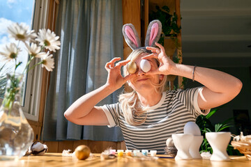 Smiling woman preparing easter decoration at home, painting colorful easter eggs and coloring egg...