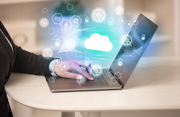 Hands working on laptop with digital icons